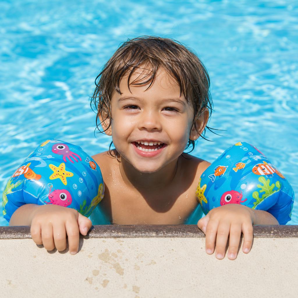 Child holding onto pool edge with colorful armbands